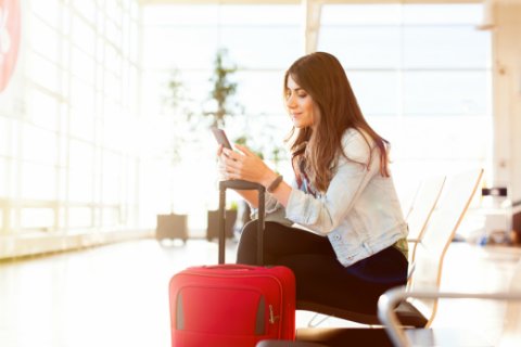 mujer en aeropuerto investigando en su telefono como marcar a mexico desde el extranjero